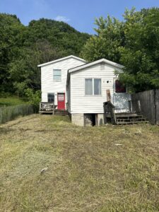 Front view of single-family detached home at 408 & 410 3rd Avenue, Beaver Falls PA, white siding with red doors, Eastvale neighborhood, ready for investor or homebuyer.