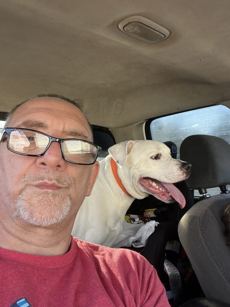 Marcus Geiser smiling beside his big American Bulldog, Diesel, reflecting loyalty, comfort, and the simple joys of companionship during recovery