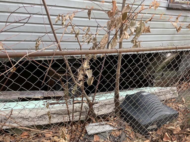 Collapsed and inward-bowed foundation wall on the right side of a duplex, exposing the basement and showing structural failure requiring full foundation replacement.