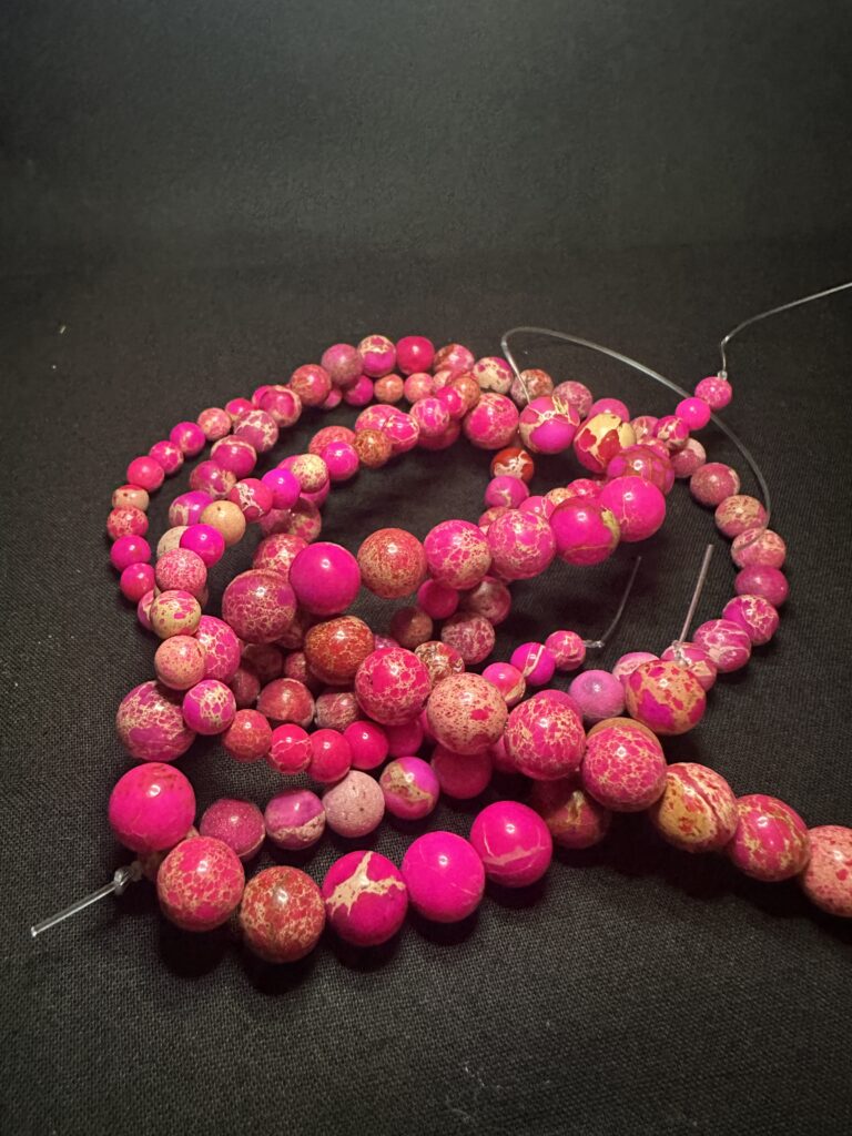 Amethyst in multiple forms — raw crystal, polished round beads, faceted beads, and tube cuts — illustrating natural variation documented in the Stone Library.