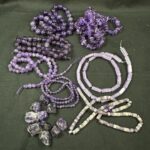 Assorted amethyst beads and raw amethyst crystals showing variation in color saturation, cut, and natural formation used in jewelry design