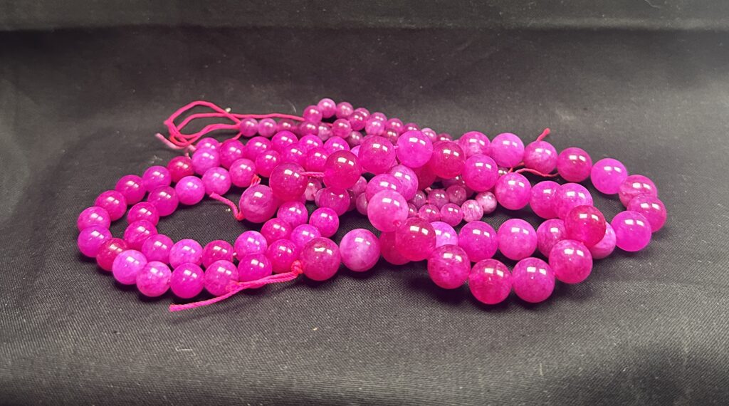 Strand of hot pink tourmaline gemstone beads with vibrant color and polished round finish